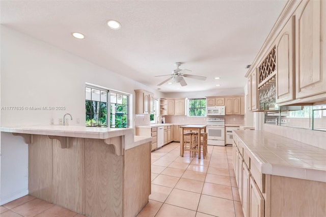 13925 SW 74th Ave, Palmetto Bay, FL 33158 - kitchen featuring a kitchen bar, tile counters, light brown cabinetry, and white appliances