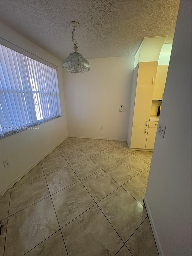 10133 NW 24th Pl Unit 206, Sunrise, FL 33322 - unfurnished dining area with baseboards, a textured ceiling, an inviting chandelier, and light tile patterned flooring