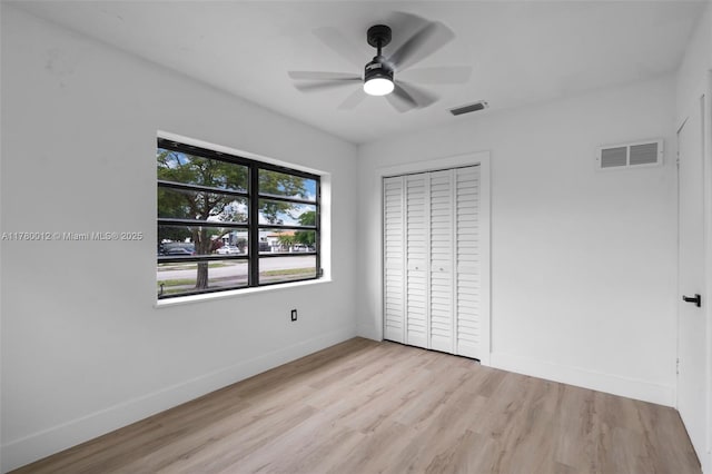 unfurnished bedroom featuring light wood-style floors, a closet, baseboards, and visible vents
