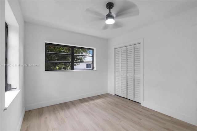unfurnished bedroom with a closet, light wood-style floors, baseboards, and ceiling fan