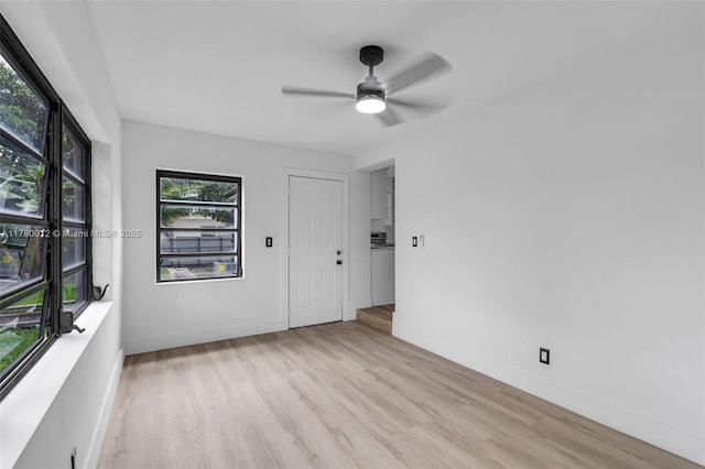 spare room featuring light wood-type flooring, baseboards, and a ceiling fan