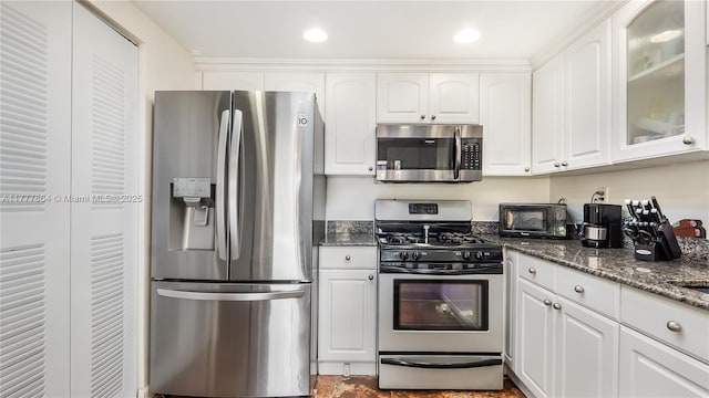 kitchen featuring dark stone counters, white cabinets, appliances with stainless steel finishes, and glass insert cabinets