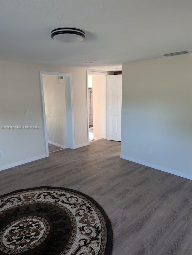 unfurnished room with visible vents, wood finished floors, and baseboards
