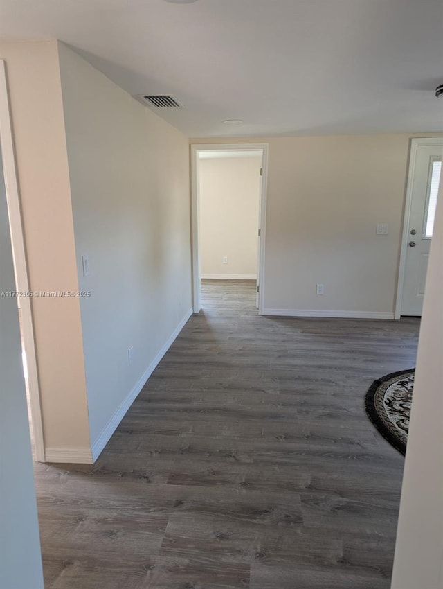 corridor with visible vents, dark wood-style floors, and baseboards