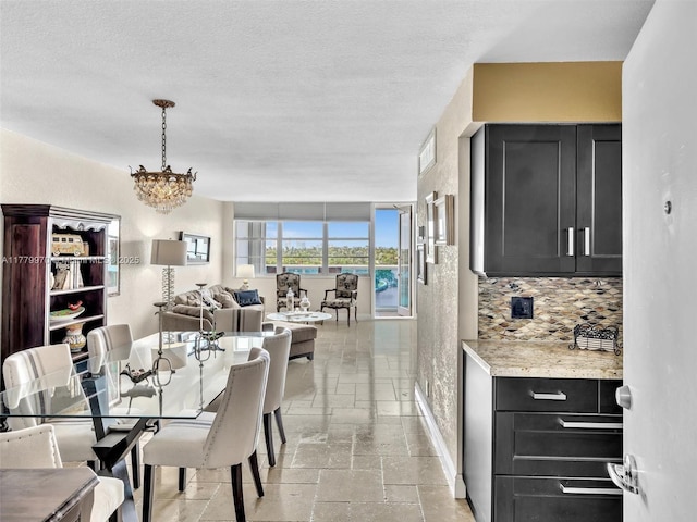 6770 Indian Creek Dr Unit 7K, Miami Beach, FL 33141 - dining area featuring stone tile floors, a chandelier, a textured ceiling, and a water view