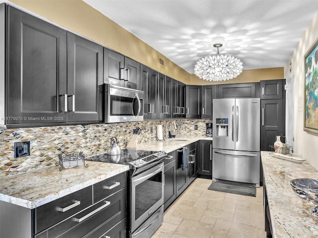 6770 Indian Creek Dr Unit 7K, Miami Beach, FL 33141 - kitchen featuring stainless steel appliances, decorative backsplash, a chandelier, and dark cabinetry