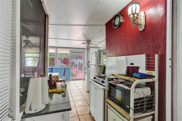 kitchen with black microwave, light tile patterned floors, ceiling fan, and range