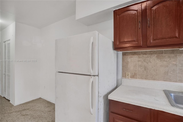 kitchen with freestanding refrigerator, light carpet, and light countertops