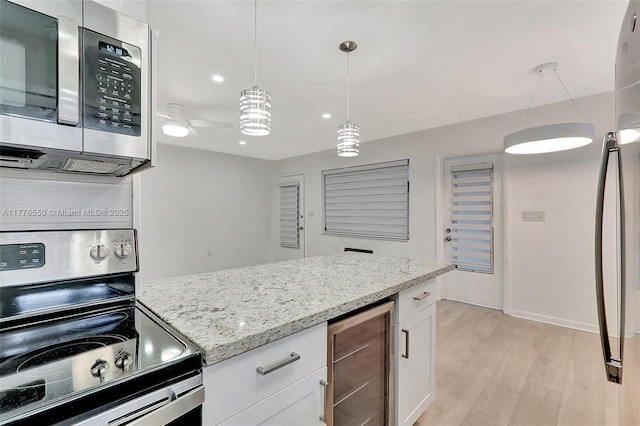 15600 NE 6th Ave Unit 30A, Miami, FL 33162 - kitchen with white cabinets, light wood-type flooring, stainless steel appliances, beverage cooler, and light stone counters