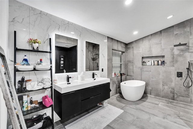 bathroom featuring a freestanding tub, tiled shower, a sink, tile walls, and double vanity