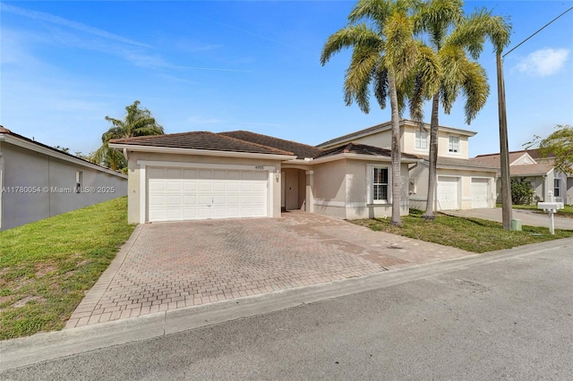 view of front of house with stucco siding, decorative driveway, and an attached garage