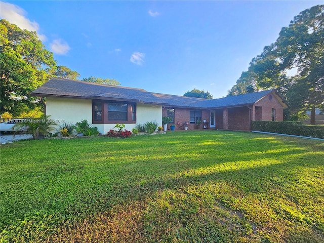 ranch-style house featuring brick siding, stucco siding, and a front yard