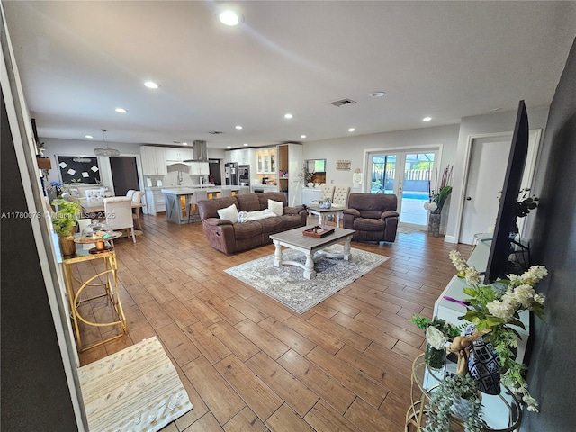 living room featuring light wood finished floors, recessed lighting, and visible vents