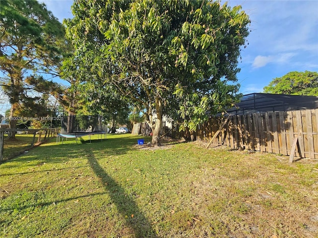 view of yard with a trampoline and a fenced backyard