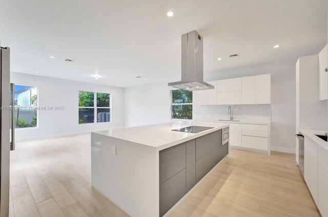 3527 Forest View Cir, Dania Beach, FL 33312 - kitchen featuring black electric cooktop, island exhaust hood, a sink, modern cabinets, and light wood-type flooring