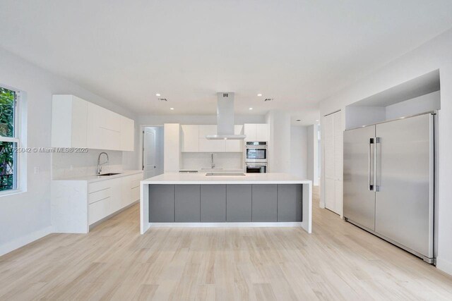 3527 Forest View Cir, Dania Beach, FL 33312 - kitchen with white cabinets, stainless steel appliances, a sink, island range hood, and modern cabinets