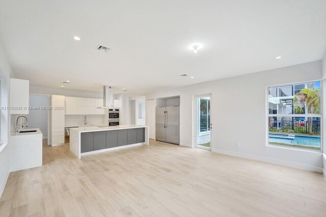 3527 Forest View Cir, Dania Beach, FL 33312 - unfurnished living room featuring baseboards, a sink, visible vents, and light wood-type flooring