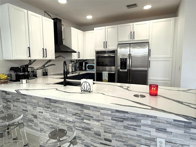 10060 NW 86th Ter, Doral, FL 33178 - kitchen featuring appliances with stainless steel finishes, wall chimney range hood, a peninsula, white cabinets, and recessed lighting