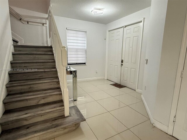 10060 NW 86th Ter, Doral, FL 33178 - entrance foyer featuring stairs, a textured ceiling, light tile patterned flooring, and baseboards