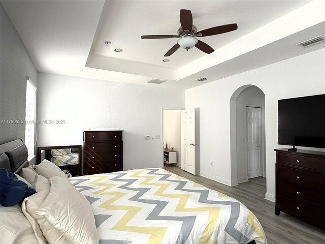 10060 NW 86th Ter, Doral, FL 33178 - bedroom with a tray ceiling, wood finished floors, arched walkways, ceiling fan, and baseboards