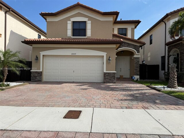 10060 NW 86th Ter, Doral, FL 33178 - mediterranean / spanish-style house with stucco siding, stone siding, decorative driveway, and a tile roof