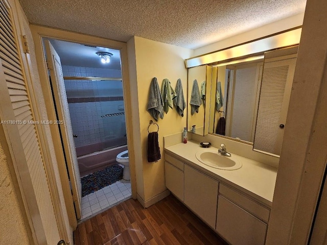 18061 Biscayne Blvd Unit 802, Aventura, FL 33160 - bathroom featuring wood finished floors, toilet, vanity, a textured ceiling, and enclosed tub / shower combo