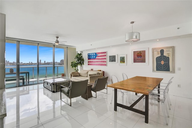 living area with floor to ceiling windows, a water view, ceiling fan, light tile patterned flooring, and a city view