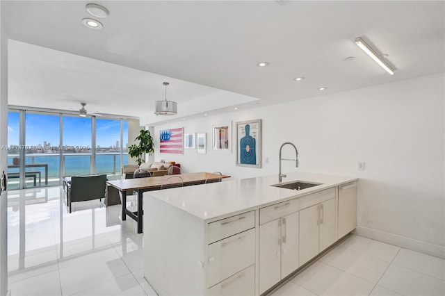 kitchen featuring a peninsula, light countertops, light tile patterned flooring, a water view, and a sink