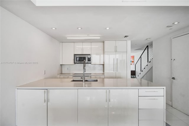 kitchen featuring white cabinetry, stainless steel microwave, modern cabinets, and recessed lighting