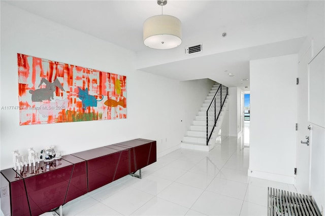 hallway with visible vents, baseboards, stairway, and light tile patterned floors