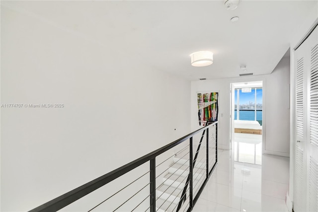 corridor with light tile patterned floors, an upstairs landing, and a water view