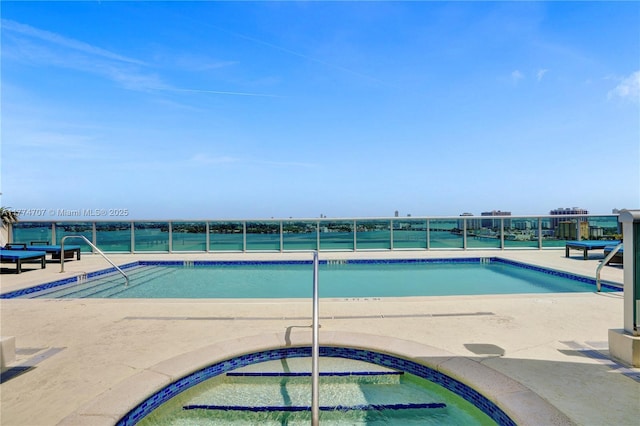 pool with a patio area and a hot tub