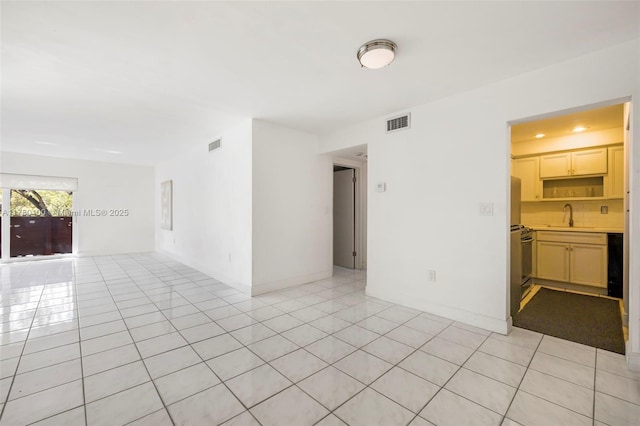 empty room featuring baseboards, light tile patterned flooring, a sink, and visible vents