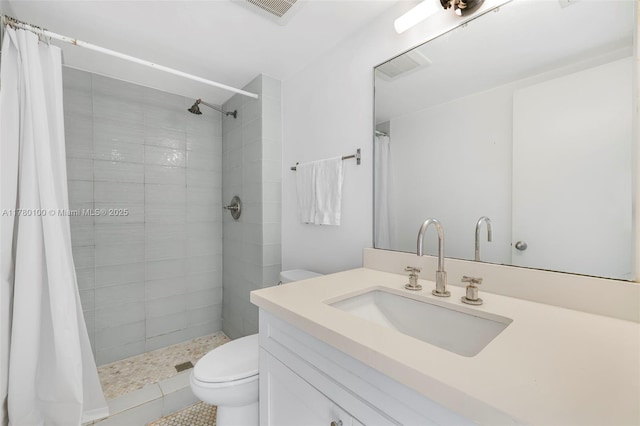 full bathroom featuring toilet, vanity, a tile shower, and visible vents