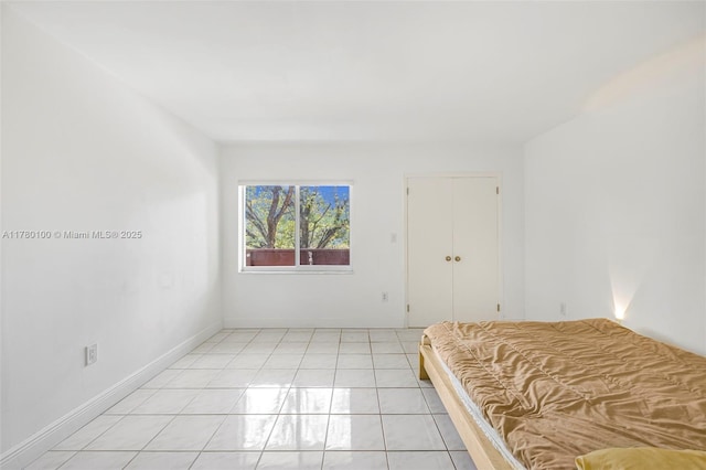unfurnished bedroom featuring light tile patterned floors and baseboards
