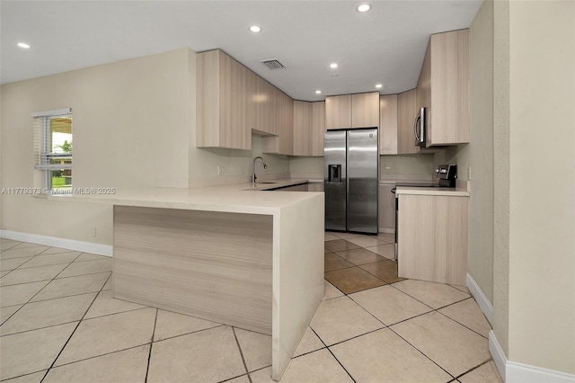 411 NE 58th Ct, Oakland Park, FL 33334 - kitchen with light tile patterned floors, light countertops, a peninsula, and appliances with stainless steel finishes