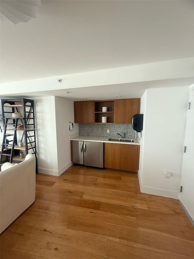 kitchen featuring baseboards, light countertops, open shelves, brown cabinets, and dishwasher