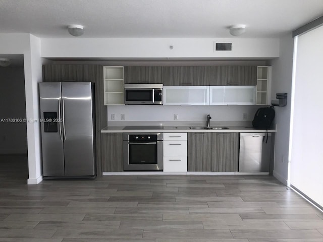 kitchen featuring visible vents, a sink, open shelves, and appliances with stainless steel finishes