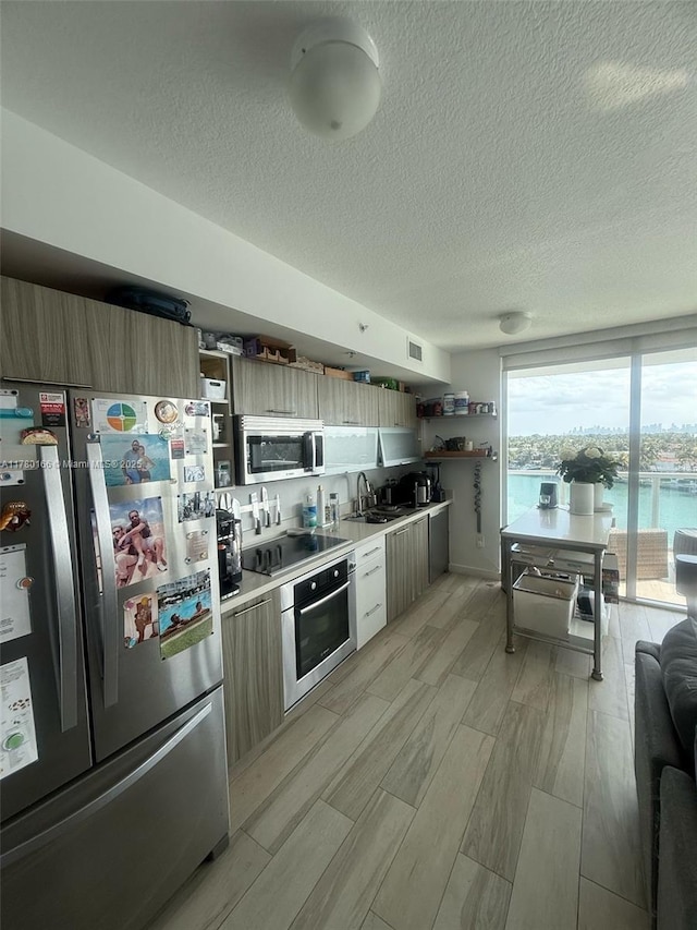 kitchen with light countertops, a sink, open shelves, and appliances with stainless steel finishes