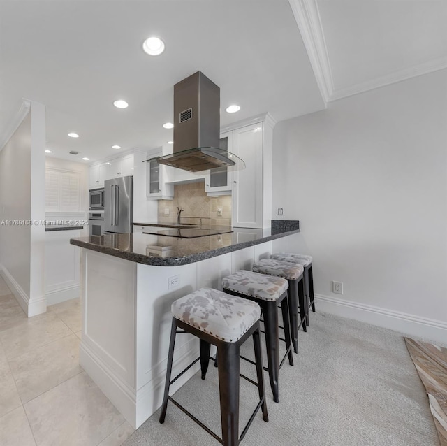 kitchen featuring white cabinets, stainless steel appliances, island range hood, a sink, and a peninsula