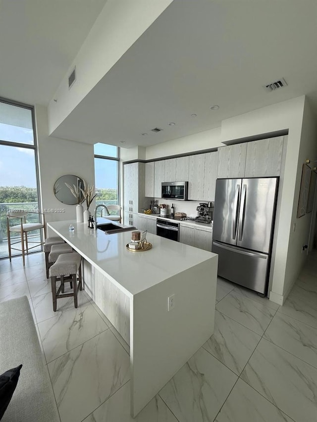 2000 Metropica Way Unit 603, Sunrise, FL 33323 - kitchen featuring appliances with stainless steel finishes, floor to ceiling windows, light marble finish flooring, modern cabinets, and healthy amount of natural light