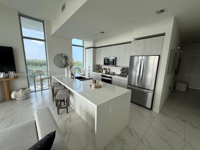 2000 Metropica Way Unit 603, Sunrise, FL 33323 - kitchen featuring stainless steel appliances, light marble finish flooring, modern cabinets, an island with sink, and light countertops
