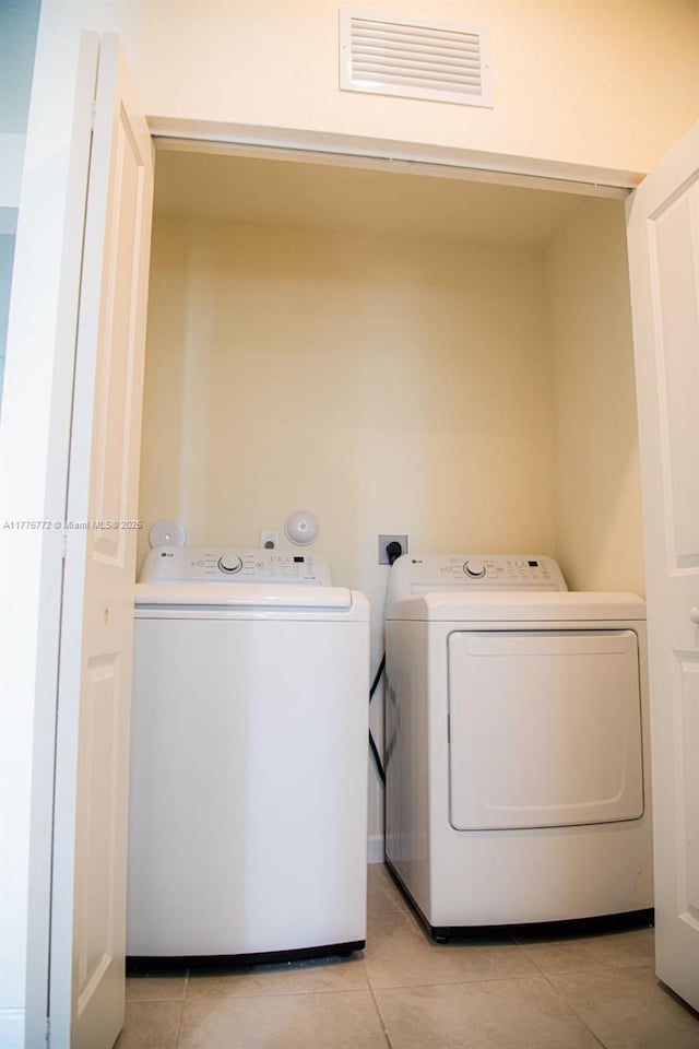 laundry room with light tile patterned floors, visible vents, laundry area, and washing machine and clothes dryer