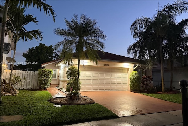 view of front of property featuring fence, stucco siding, driveway, and an attached garage