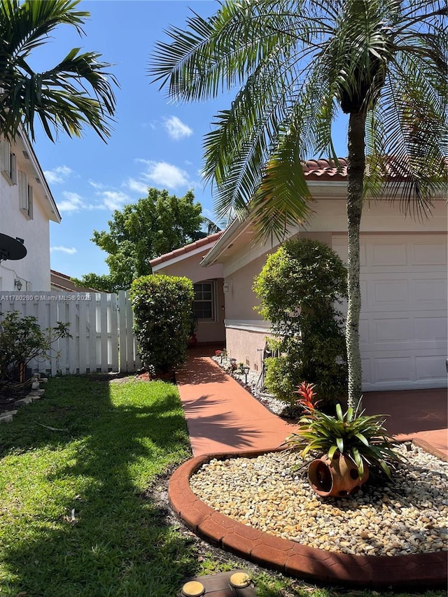 view of side of home with a garage, fence, stucco siding, and a yard