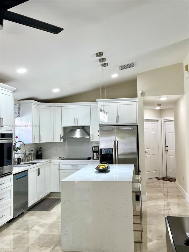 kitchen with a sink, visible vents, a kitchen island, white cabinets, and appliances with stainless steel finishes