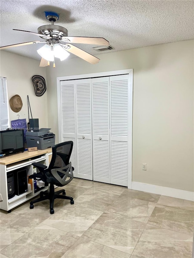 office with a textured ceiling, visible vents, ceiling fan, and baseboards