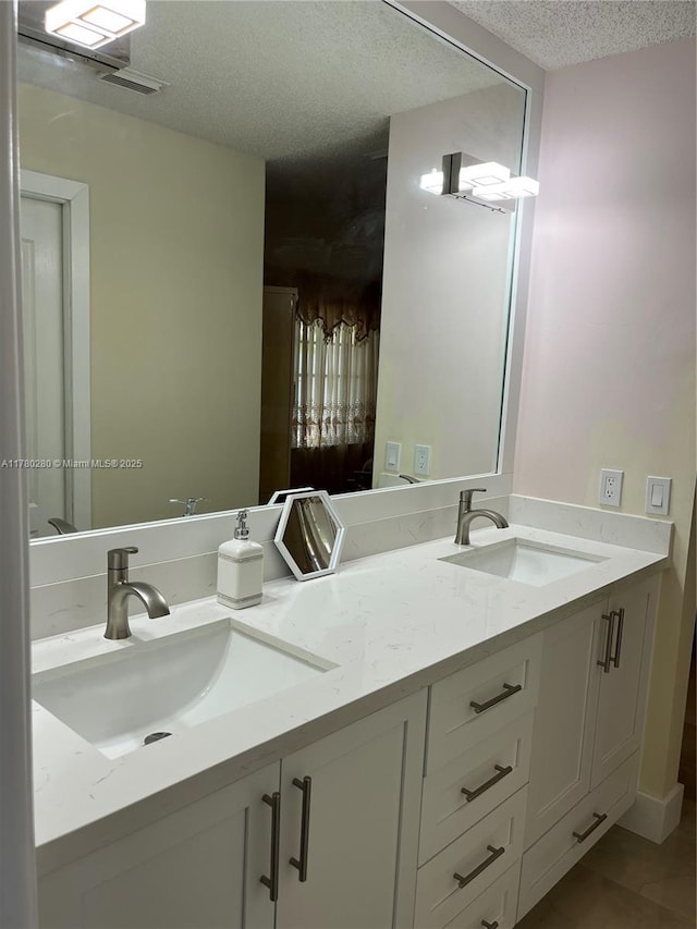full bathroom featuring tile patterned flooring, a textured ceiling, a sink, and double vanity