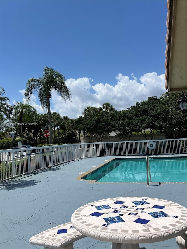 community pool featuring fence and a patio