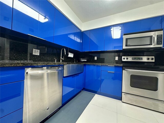kitchen featuring tasteful backsplash, modern cabinets, blue cabinets, and appliances with stainless steel finishes
